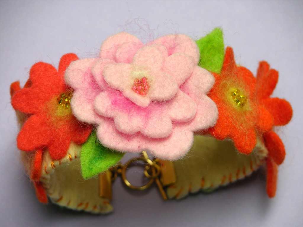 a felt cuff decorated with pink and orange felt flowers